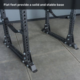 Two Bells of Steel Manticore Flat Foot Power Rack Builder bases (3" x 3", 1" holes) with multiple bolt holes and flat feet rest on a tiled floor. Perfect for a home gym setup, the text above reads, "Flat feet provide a solid and stable base.