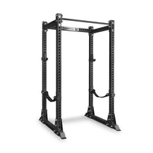 The Bells of Steel Manticore Flat Foot Power Rack - Prebuilt (3" x 3", 1" Holes) is a black metal rack for weightlifting, featuring durable 3x3 uprights with multiple 1-inch holes for adjustable attachments, two safety straps, and a pull-up bar at the top—making it an ideal centerpiece for any home gym. Shown here on a white background.