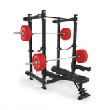 The Bells of Steel Manticore Folding Power Rack Builder (3"x3", 1" holes) with a bench and two barbells loaded with red weight plates stands against a plain white background—ideal for any home gym.