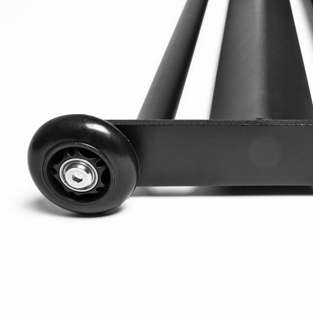 Close-up of Bells of Steel's Glute Ham Slider, a sleek black metal object with a round black wheel at one end. Its smooth, reflective surface emphasizes its space-efficient design against a white backdrop.