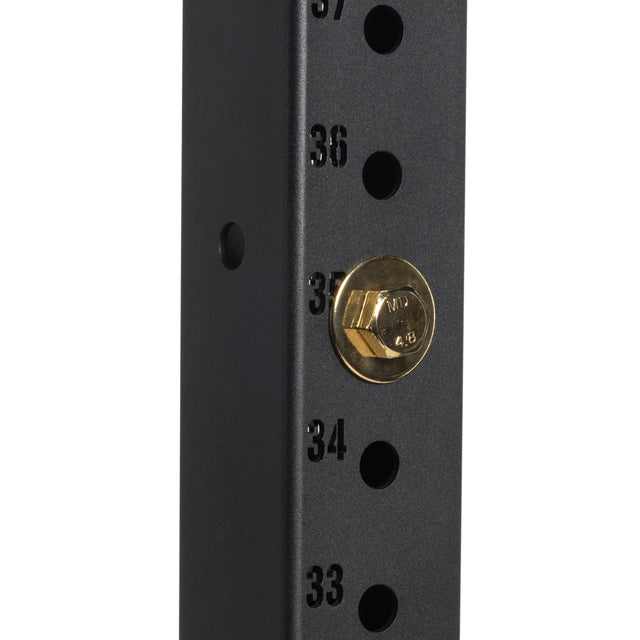 A close-up of the black metal frame from the Hydra Series showcases numbered holes ranging from 33 to 37, with a Gold / Black Titanized Bolt by Bells of Steel Canada securely fitted in hole number 35. The design implies adjustable settings for equipment assembly or structural support.