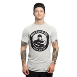 A young man wearing a backward black cap and a light gray Bells of Steel Bamboo T-Shirt stands facing forward, showing tattooed arms, against a plain white background.