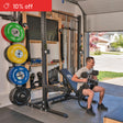 A man smiles while lifting dumbbells on an adjustable bench in his garage, surrounded by neatly organized Bells of Steel Home Gym Builder racks, weight plates, and barbells. A "10% off" sale banner appears in the top left corner.