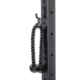 A black tricep rope with solid rubber ends and a metal carabiner hangs from the Bells of Steel Utility Hook on a gym rack, showcasing numbered height markings and round holes—a smart All-in-One Trainer storage solution.