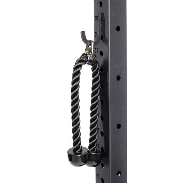 A black tricep rope with solid rubber ends and a metal carabiner hangs from the Bells of Steel Utility Hook on a gym rack, showcasing numbered height markings and round holes—a smart All-in-One Trainer storage solution.