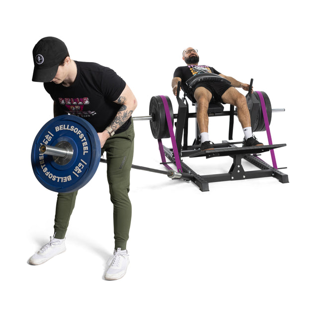 A man in a black cap and shirt uses a landmine attachment for barbell workouts, while another uses the Bells of Steel Hip Thrust Machine. Both are focused on their exercises in the bright, minimalistic gym space.