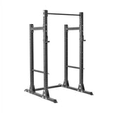 The Bells of Steel Hydra Half Rack Builder is a sturdy gray rack with modular components, adjustable support brackets, a pull-up bar at the top, pre-drilled ⅝" holes for extra equipment, and wide base supports—ideal for weightlifting and strength training.