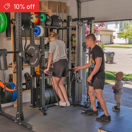 A woman does dips on gym equipment in a home garage where Bells of Steel’s Hydra Storage Builder shelves are visible. A man spots her, a child stands nearby, and a "10% off" discount banner appears in the top left corner.