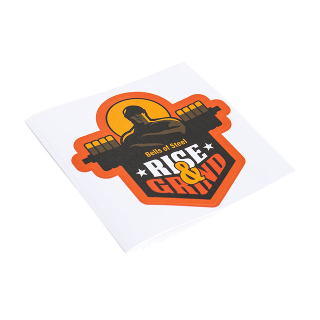 Vinyl die-cut sticker showcasing a stylized illustration of a muscular figure holding a barbell on their shoulders, featuring the words "Bells of Steel" and "Rise & Grind" in bold letters. The durable design is set against an orange and red background and comes with free shipping.