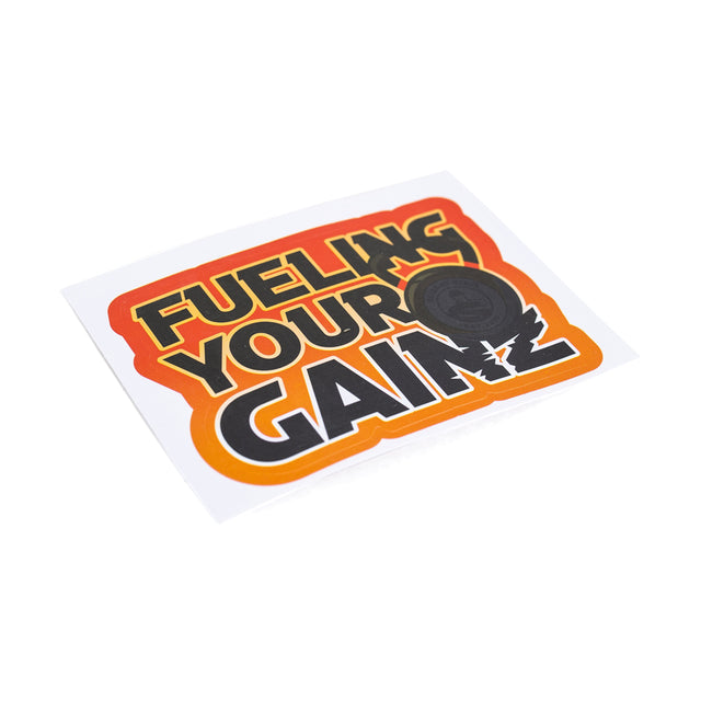 Sticker showcasing bold "Fueling Your Gainz" text in a striking red, orange, and black gradient. The robust design includes a small black barbell illustration set against a white background. These vinyl die-cut stickers from Bells of Steel are available with free shipping.