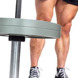 Close-up of muscular legs in black athletic shoes standing by a loaded barbell secured with Bells of Steel Magnetic Clamp Collars in a gym setting.