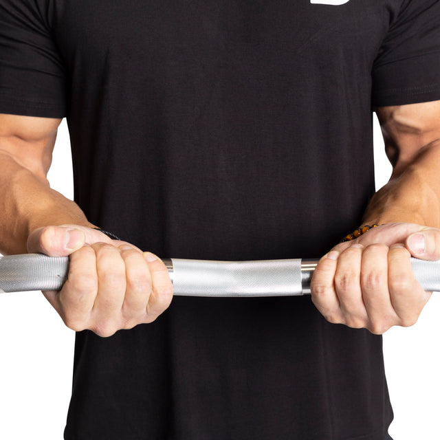 Clad in a black shirt, a person grips a steel rod with strength similar to their technique with Bells of Steel's Fixed Barbells - Easy Curl. The rod shows a slight bend under pressure.