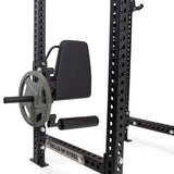 A Bells of Steel Leg Curl / Leg Extension Rack Attachment, in black, mounts to a power rack and features a padded backrest, round weight-loading plate, and horizontal padded bar.