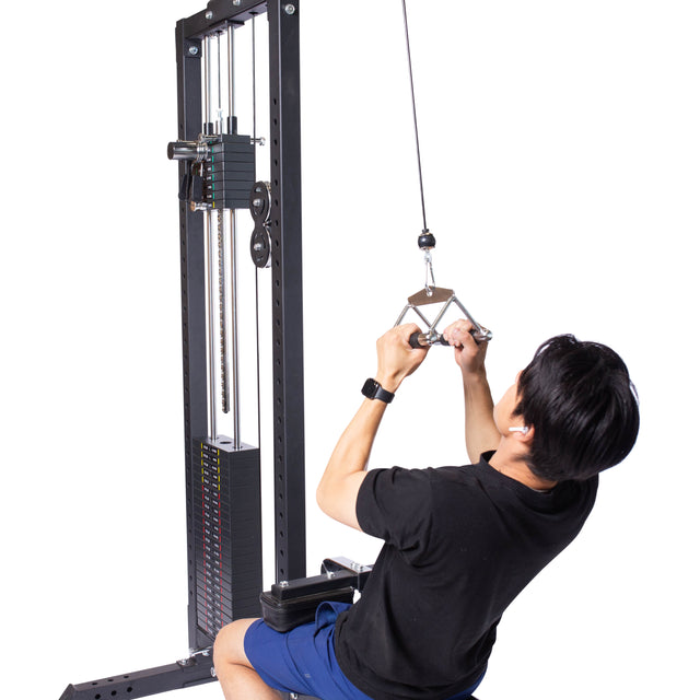 Wearing a black shirt and blue shorts, an individual uses a seated cable row machine with intense focus, expertly pulling on the Bells of Steel Double D Handle Cable Attachment connected to a weight stack by a cable against a plain white background.