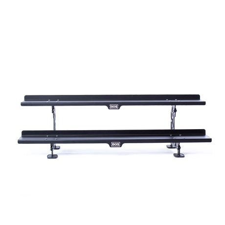Two black, rectangular metal shelves from the Bells of Steel Commercial Interchangeable Weight Rack (Components Only) are stacked horizontally and supported by metal brackets, ideal for storing competition kettlebells.
