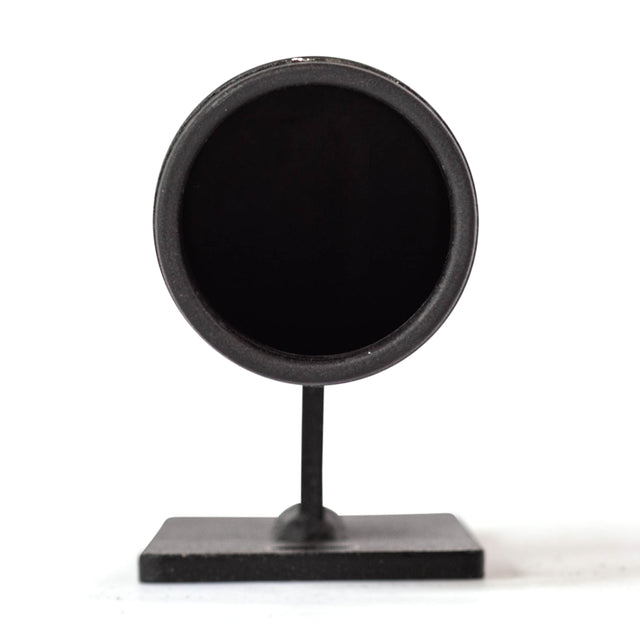 A sleek black circular object mounted on a stand, resembling a small flat dish or lens, is positioned against a plain white background. It brings to mind essential home gym organization tools like the Bells of Steel Vertical Mount Barbell Holder Rack Attachment for maintaining order and style.