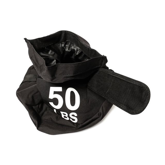 A Bells of Steel Fitness Sandbag featuring a wide opening and carrying strap, crafted from durable Condura material with "50 LBS" in bold white text. The black bag is slightly open, revealing its inner lining, making it ideal for intense sandbag workouts.