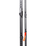 Close-up of the Bells of Steel Light Commercial Power Rack (2.3" x 2.3", ⅝" holes) in black metal, featuring evenly spaced holes, a silver latch, and an orange resistance band—perfect for safer barbell training at home. White background.