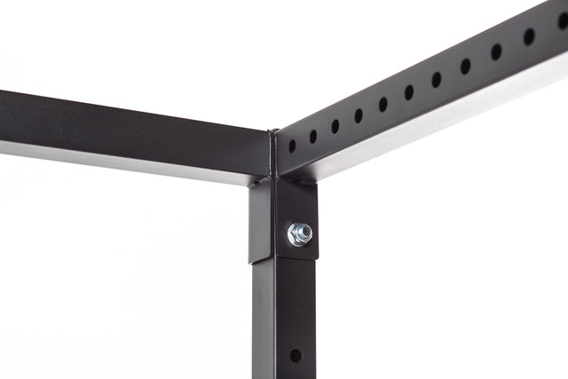 The image showcases a close-up of a corner from the Residential Power Rack by Bells of Steel, featuring a black metal frame fastened with a bolt joining two sections. Its sleek and minimalist design is perfect for a home gym setup. The frame includes evenly spaced ⅝" holes for adjustable assembly, making it ideal for components like j-cups, all set against a plain white background.