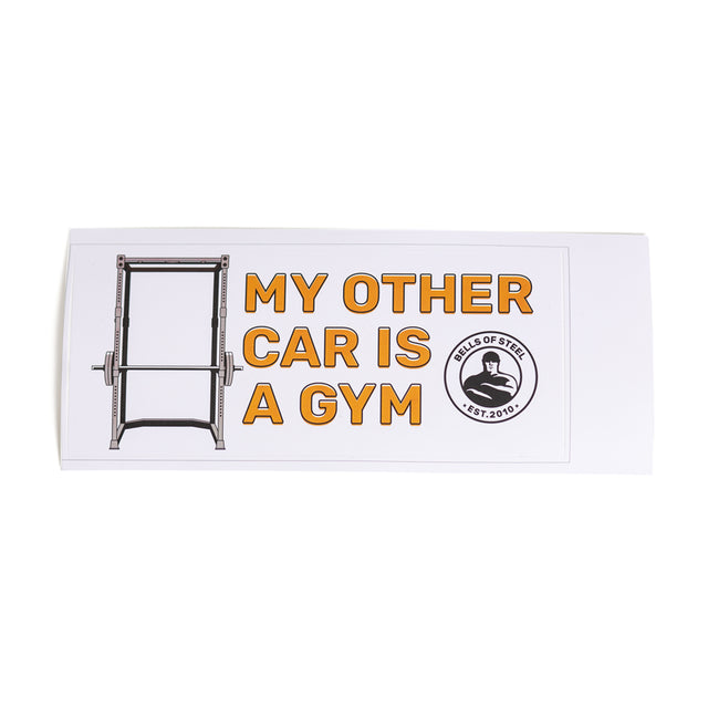 A rectangular vinyl die-cut sticker from Bells of Steel showcases an image of a squat rack alongside the striking text "MY OTHER CAR IS A GYM," while a circular logo featuring a weightlifter icon enhances the right side. Enjoy free shipping on this durable design, set against a sharp white background.