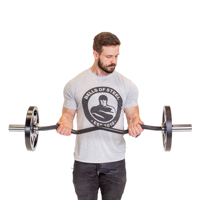 A man in a gray Bells of Steel t-shirt demonstrates a bicep curl with the EZ Curl Bar (47"), focusing on arm development, against a plain white background.