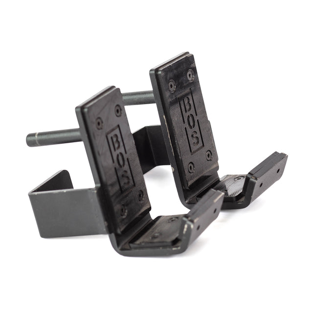 Introducing the Bells of Steel Standard J-Cups: a pair of black metal hooks featuring a durable design for holding items, each emblazoned with the BOS logo. These J-Cups are engineered to attach to a power rack's horizontal bar, offering UHMW protection and a solid frame for enhanced support.