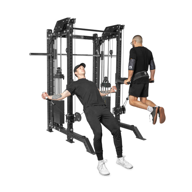 Two men are working out at the gym. One is doing cable flys using THE KOLOSSOS - Smith Functional Trainer by Bells of Steel, while the other does dips on parallel bars. Both wear black athletic gear with a multifunctional cable and pulley machine in the background.