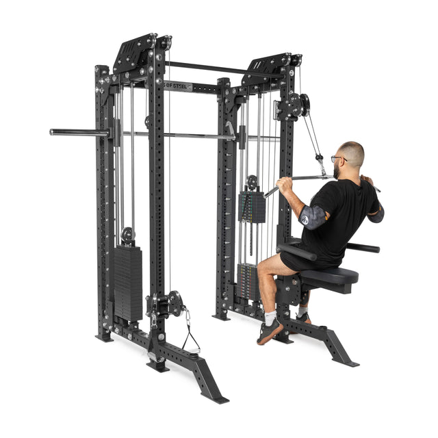 A person uses THE KOLOSSOS - Smith Functional Trainer by Bells of Steel in a gym, pulling handles towards their torso to work their back muscles. This machine features an adjustable weight stack and robust metal frame, making it ideal for any home gym setup.