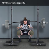 A man with tattoos and knee sleeves squats a loaded Bells of Steel Safety Squat Bar - The SS4 on a rack. Text above says "1500lbs weight capacity." Perfect gear for your next leg day.