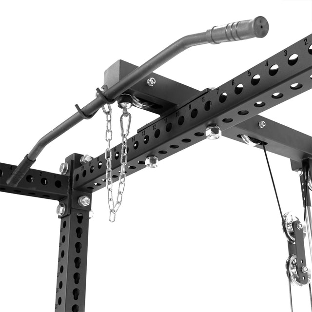 Close-up of a home gym setup showcasing Bells of Steel's Lat Pulldown & Low Row Rack Attachment for Hydra & Manticore featuring a black metal pull-up bar with numbered slots, chain fitting, and equipped with pulleys and bolts for versatile cable workouts.