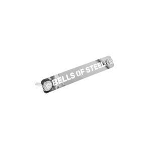 A metal nameplate engraved with the brand "Bells of Steel" is attached to the Hydra Hardware, part of a power rack setup. It features two protruding bolts on each side and is set against a plain white background.