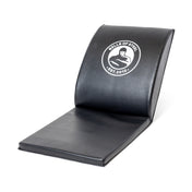 A black Luxury Sit Up Mat by Bells of Steel features a white logo with a weightlifter and "Bells of Steel Est. 2010." This ergonomic mat has a curved cushion for optimal lumbar support during ab exercises.