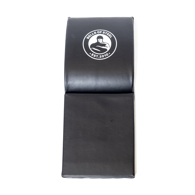 Bells of Steel Luxury Sit Up Mat, black and foldable with "BELLS OF STEEL" and "EST. 2010." Designed for lumbar support, it features two sections for easy portability and is showcased vertically on a white background.