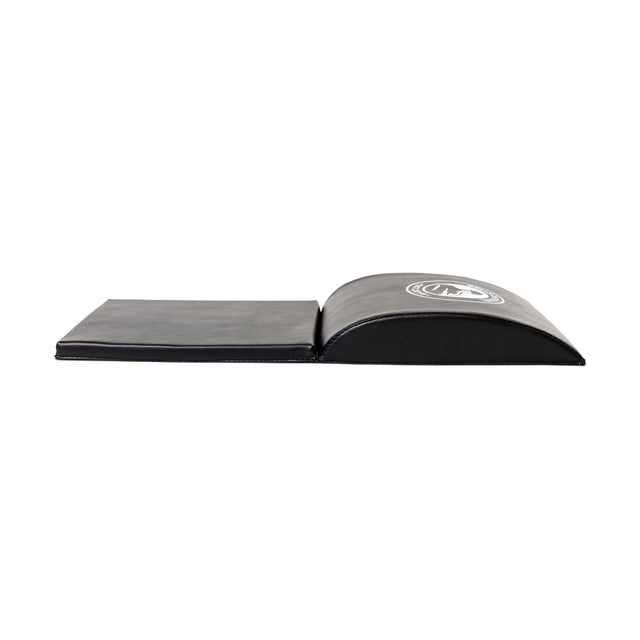 A partially open black Luxury Sit Up Mat by Bells of Steel features a slightly inclined surface and visible brand logo. This portable mat supports lumbar curvature, making it ideal for abdominal exercises and fitness routines.