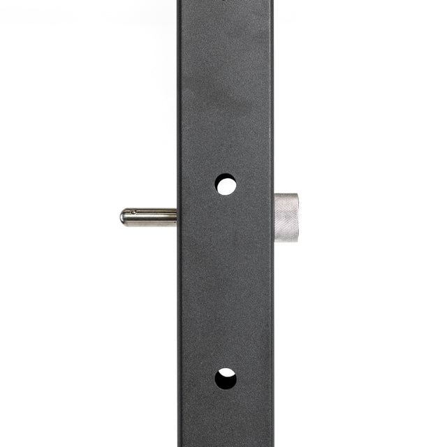 A close-up of a Bells of Steel Vertical Metal Bar shows one of their Magnetic Rack Attachment Pins inserted into a hole. The bar, possibly anodized aluminum, has a dark gray textured finish for enhanced durability and appearance.