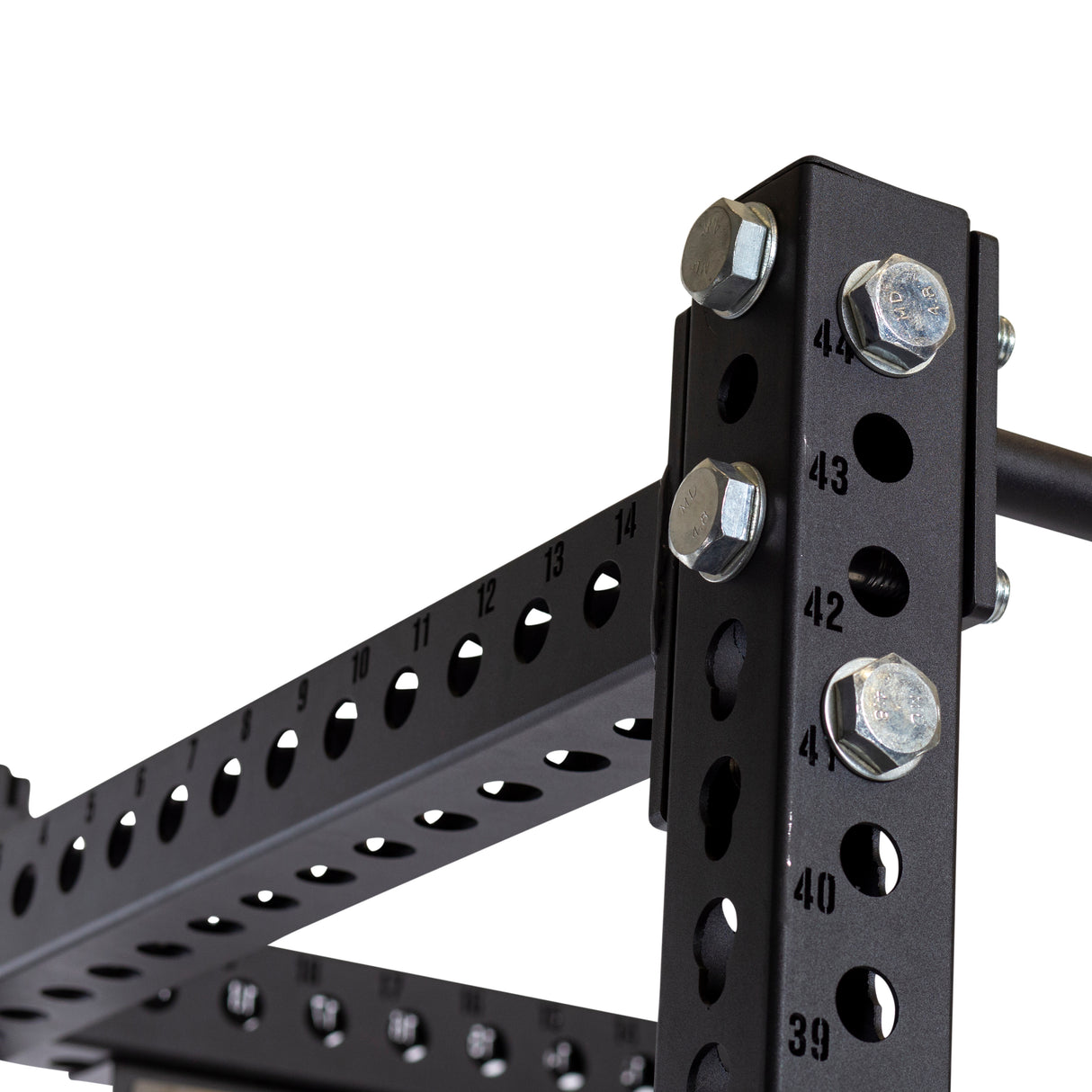 The image showcases a close-up of the Manticore Four Post Power Rack Builder by Bells of Steel, crafted from black metal with numbered holes and bolts. This power rack's frame measures 3" x 3" and is equipped with 1" holes, making it easy to adjust attachments on its vertical and horizontal beams. Its modular components make it an ideal addition to any home gym setup.