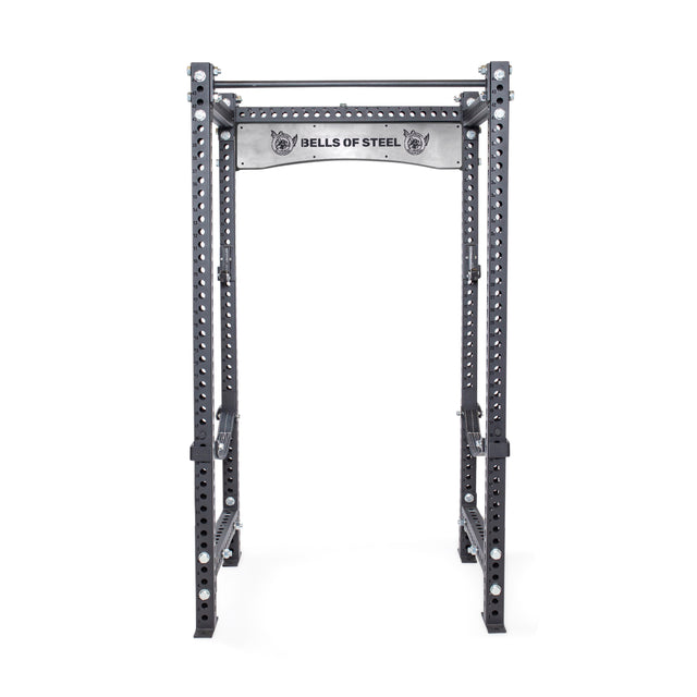 A great addition to any home gym, the Manticore Four Post Power Rack Builder features a grey metal frame with numerous 1-inch holes for versatile adjustments. The top beam proudly displays the "Bells of Steel" brand name. It's specifically designed for strength training exercises and supports a variety of modular components.