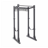 The Manticore Flat Foot Power Rack Builder, crafted with robust black steel and featuring 3" x 3" posts with 1" holes for adjustable settings, includes a pull-up bar at the top. It offers a sturdy freestanding design on the floor and can support up to 1,000 pounds. The "Bells of Steel" brand name is prominently displayed on the crossbar.