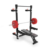 The Bells of Steel Manticore Folding Half Rack - Prebuilt features a sleek black and red color scheme, making it an ideal fit for a small home gym. With its included weight bench and barbell equipped with red weight plates, this rack offers a 1,000-pound capacity perfect for strength training exercises such as bench presses and squats.