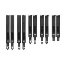 Nine black Mighty Wrist Wraps from Bells of Steel are laid out vertically on a white background. Each wrap features a rectangular Velcro patch and distinctive branding on the ends, resembling powerlifting or gym essentials.