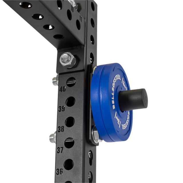 Close-up of Bells of Steel Bolt-On Plate Pegs mounted on a black power rack with numbered holes, holding a blue Olympic-style weight plate and secured by bolts.