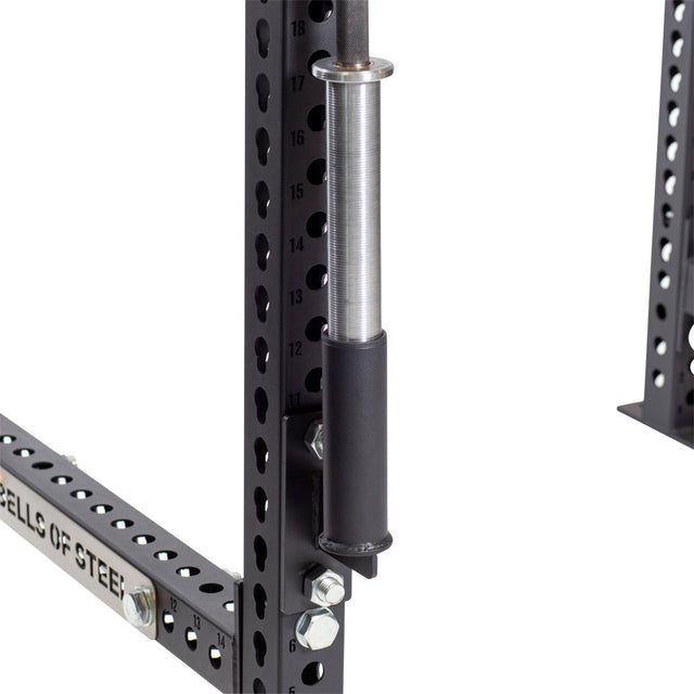 Close-up of a black metal power rack with numbered holes featuring the Bells of Steel Vertical Mount Barbell Holder Rack Attachment, designed for gym equipment. Bolts are visible securing parts of the structure, making it perfect for home gym organization.