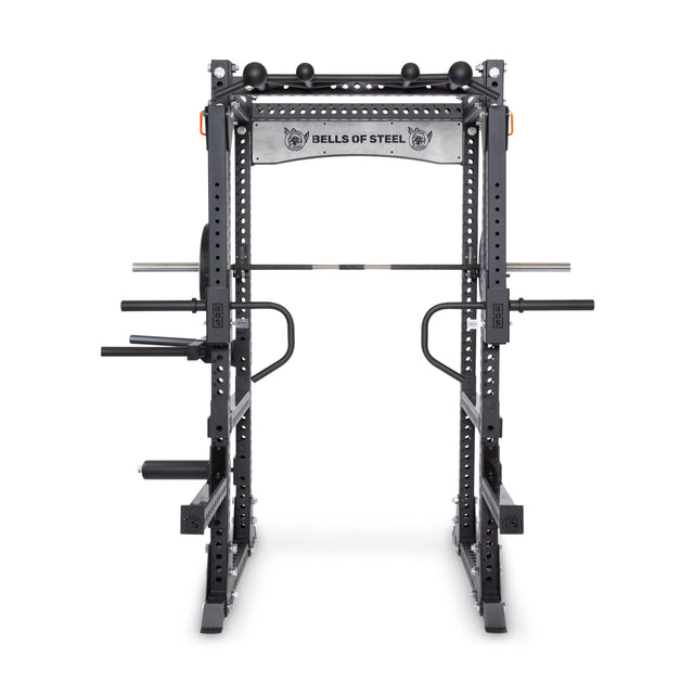 Against a plain white backdrop, the Manticore Flat Foot Power Rack Builder (3" x 3", 1" Holes) is prominently displayed, featuring various attachments like a pull-up bar and dip handles. The brand name "Bells of Steel" is proudly emblazoned across the top crossbar, showcasing its open ecosystem flexibility.
