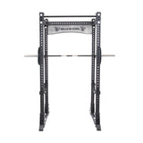 The Manticore Flat Foot Power Rack Builder by Bells of Steel securely holds a durable barbell set on its solid hooks. Made from black metal featuring multiple 1-inch adjustment holes, it proudly displays the brand's logo at the top. This versatile setup is ideal for intense workouts, set against a plain white background.
