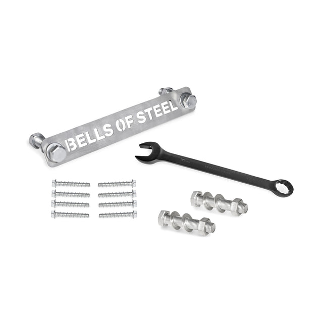 A steel bar marked "Bells of Steel" sits among bolts, nuts, and washers from the Manticore Hardware kit. A 13/16" and 20 mm black combination wrench is nearby for easy assembly of your Manticore Power Rack against a plain white backdrop.