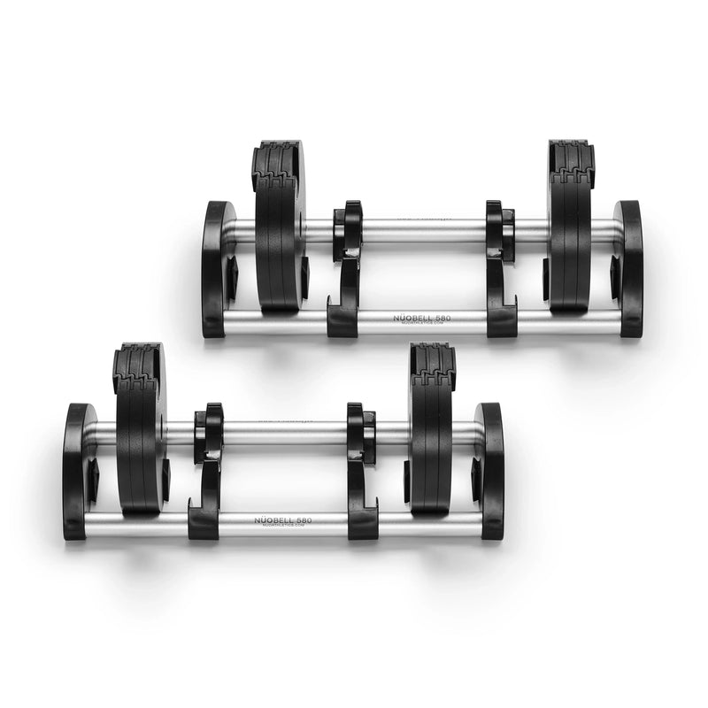 Two Nuobell adjustable dumbbells with black weight plates and chrome handles rest side by side on matching chrome and black stands against a white background. Perfect for strength training, these dumbbells are compatible with the NÜOBELL 50 to 80 LB Expansion Kit - Standard (Chrome).