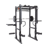 The Manticore Flat Foot Power Rack Builder, crafted from sturdy black steel and emblazoned with the "Bells of Steel" brand, serves as an open ecosystem for strength training. It is equipped with a barbell, weight plates, and versatile attachments. Featuring adjustable safety bars and pull-up bars at the top, this rack invites limitless workout possibilities.