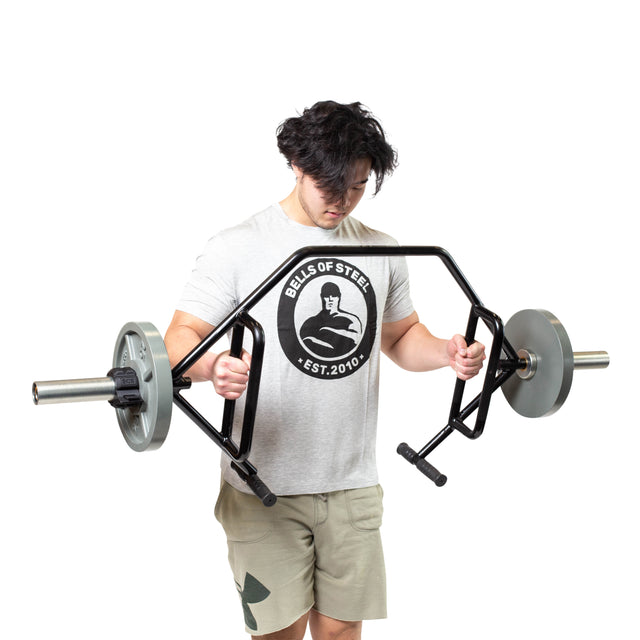 A person wearing a gray t-shirt and beige shorts is holding the Bells of Steel Open Trap Bar / Hex Bar, positioned in a deadlift stance against a plain white background.