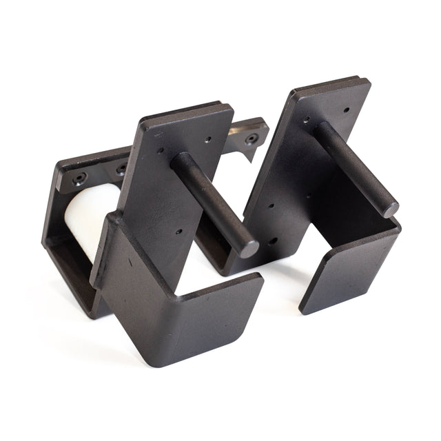 These black metal wall brackets from Bells of Steel, known as Roller J-Cups, boast a minimalist design with each piece featuring a horizontal rod for support. Positioned against a white background, they highlight their robust construction and modern aesthetic.