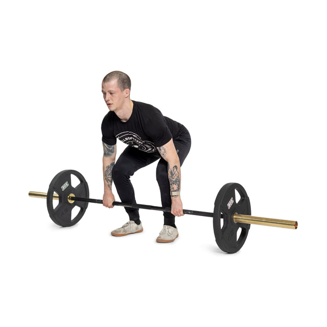 A person in a black shirt and pants is executing a deadlift with a barbell equipped with Bells of Steel Canada Rubber Coated Iron Weight Plates. Their tattooed arms flex impressively as they lift in the gym environment, demonstrating strength and precision.